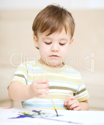 Little boy is playing with paints