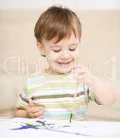 Little boy is playing with paints