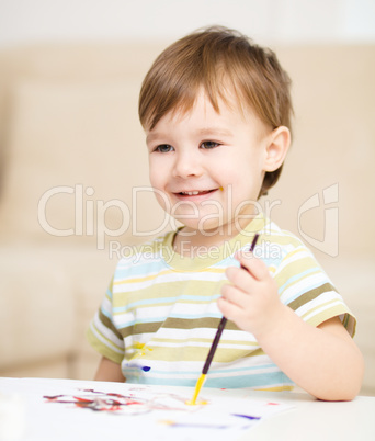 Little boy is playing with paints