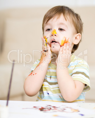 Little boy is playing with paints