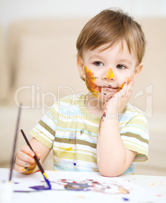 Little boy is playing with paints