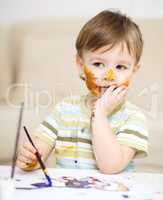 Little boy is playing with paints