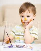 Little boy is playing with paints