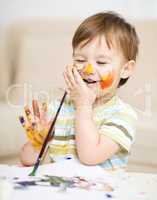 Little boy is playing with paints