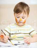 Little boy is playing with paints