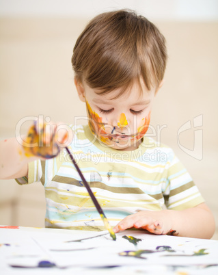 Little boy is playing with paints