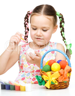 Little girl is painting eggs preparing for Easter