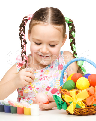 Little girl is painting eggs preparing for Easter