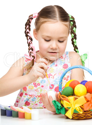 Little girl is painting eggs preparing for Easter