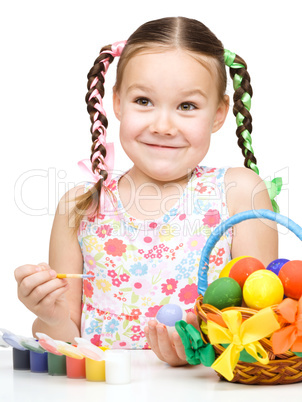 Little girl is painting eggs preparing for Easter