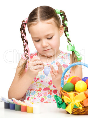 Little girl is painting eggs preparing for Easter