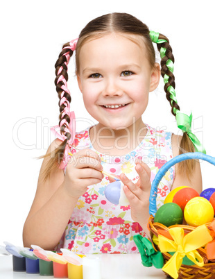 Little girl is painting eggs preparing for Easter