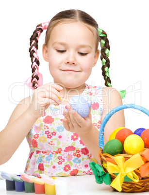 Little girl is painting eggs preparing for Easter