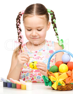 Little girl is painting eggs preparing for Easter