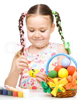 Little girl is painting eggs preparing for Easter