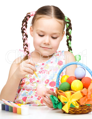 Little girl is painting eggs preparing for Easter