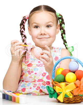 Little girl is painting eggs preparing for Easter