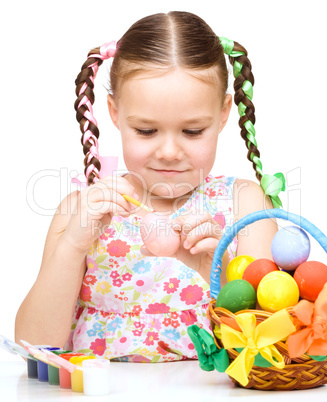 Little girl is painting eggs preparing for Easter