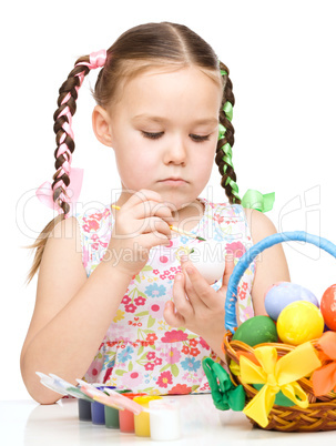 Little girl is painting eggs preparing for Easter