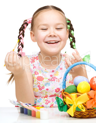 Little girl is painting eggs preparing for Easter