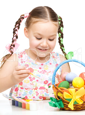 Little girl is painting eggs preparing for Easter