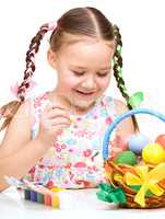 Little girl is painting eggs preparing for Easter