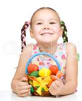 Little girl with basket full of colorful eggs