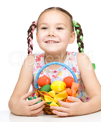 Little girl with basket full of colorful eggs