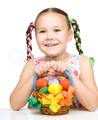 Little girl with basket full of colorful eggs