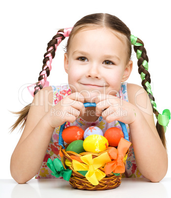 Little girl with basket full of colorful eggs