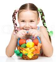 Little girl with basket full of colorful eggs