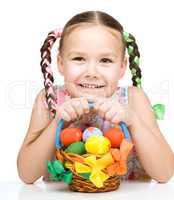 Little girl with basket full of colorful eggs