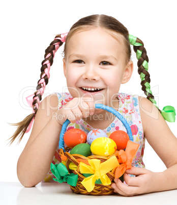 Little girl with basket full of colorful eggs