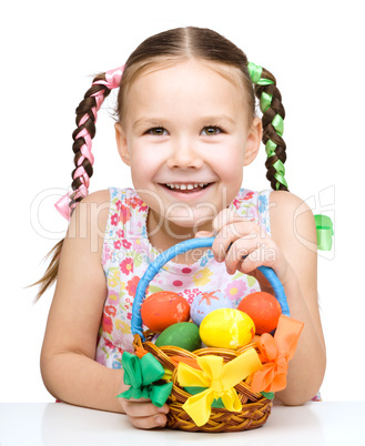 Little girl with basket full of colorful eggs