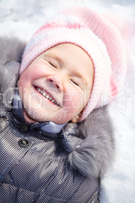 Little girl is laying on a snow
