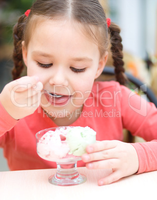 Little girl is eating ice-cream in parlor