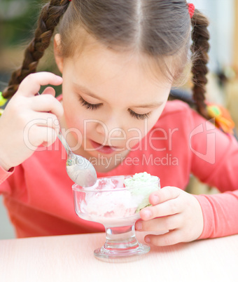 Little girl is eating ice-cream in parlor