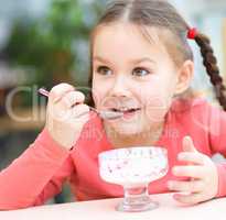 Little girl is eating ice-cream in parlor