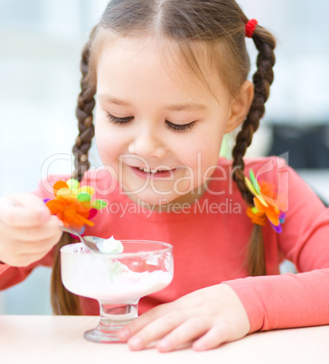 Little girl is eating ice-cream in parlor