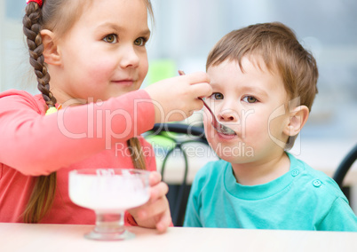Girl is feeding his little brother with ice-cream