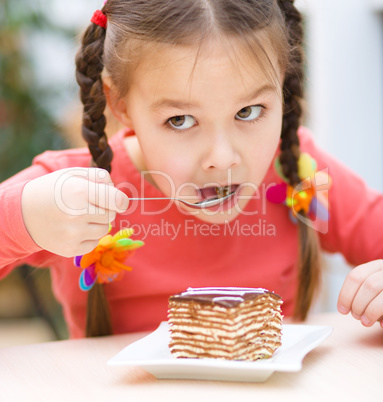 Little girl is eating cake in parlor