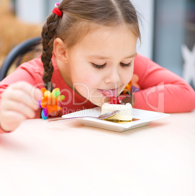 Little girl is eating cake in parlor