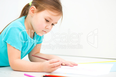 Little girl is drawing using pencils