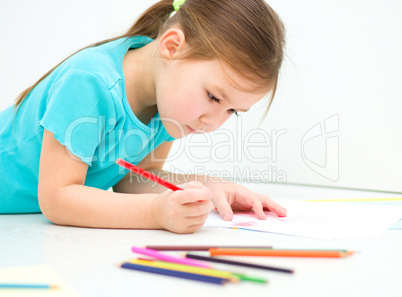 Little girl is drawing using pencils