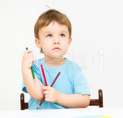 Little boy is drawing on white paper