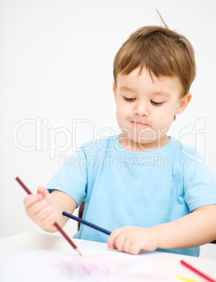 Little boy is drawing on white paper