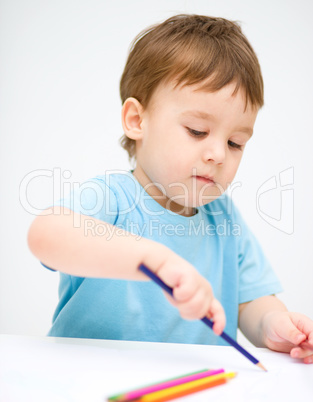 Little boy is drawing on white paper