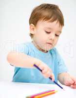 Little boy is drawing on white paper