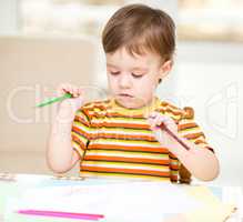 Little boy is drawing on white paper