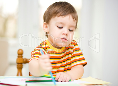 Little boy is drawing on white paper